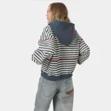 Campera con cierre y capucha, de calce oversize, con diseño de rayas horizontales en tonos blanco roto y gris/azul oscuro. Presenta un estampado frontal en rojo con el texto "EMESTUDIOS" y debajo "Always Grateful".