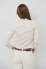 Polera de manga larga con cuello alto y detalle de volados en el borde. Confeccionada en tejido acanalado de textura suave y ajuste al cuerpo.