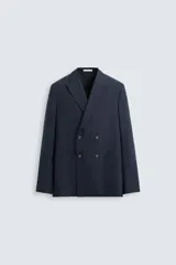 Blazer regular fit color azul marino, confeccionada en tejido con lana. Presenta cuello con solapas de pico, manga larga con puño abotonado, bolsillos de vivo en el pecho y de plastrón en la cadera. Incluye un bolsillo interior y aberturas en la espalda. El cierre es frontal con botonadura cruzada.