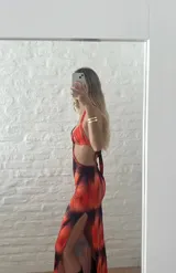 Vestido largo con estampado abstracto en tonos naranja y azul, con escote halter y aberturas laterales en la cintura.