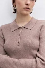 Jersey de punto color beige con cuello polo y cierre frontal de botones. Presenta mangas largas y un ajuste entallado al cuerpo.