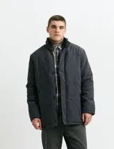 Campera de estilo Harrington en color verde oscuro, con cuello alto, cierre frontal y solapa con botones.
