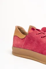 Zapatilla de cuero vacuno color rojo, con cordones al tono y suela de caucho color caramelo. Detalle de cuero vacuno color tostado en el talón.