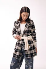 Tapado de corte recto con estampado de cuadros tartán en tonos negro y beige. Presenta solapas amplias, cierre frontal y diseño de largo medio.