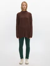 Buzo tejido color marrón con cuello alto, corte oversized y aberturas laterales.