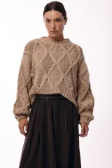 Sweater de tejido de punto grueso con diseño de rombos en relieve, cuello redondo y mangas largas amplias. Presenta una silueta relajada y holgada.
