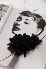 Gargantilla con cordón fino negro y aplique de dos flores grandes de tela color negro.