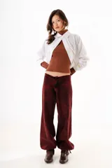 Pantalón de denim con efecto lavado, de corte recto y tiro bajo. Cuenta con cordones ajustables en los tobillos para modificar la silueta y cierre frontal con botón y cremallera.