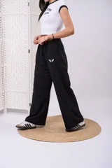 Pantalón de jogging negro de pierna ancha y corte recto, con cintura elastizada y pequeño logo bordado en blanco en el lateral.