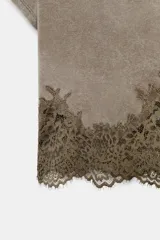 Top crop de cuello redondo y manga corta, confeccionado en tejido de algodón con efecto lavado. Presenta un bajo decorado con encaje a tono.