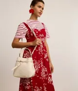 Cartera bucket pequeña de cuero sintético color negro, con doble asa (corta y larga), cierre con botón y detalle de hebilla.