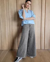 Pantalón de jean estilo wide leg, color gris con estampado sutil, de tiro medio y ruedo desflecado.