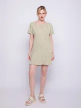 Vestido corto color verde claro, de tela con textura acanalada y cuello redondo. Es de manga corta y corte recto.