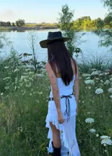 Vestido largo blanco de corte recto con escote strapless y falda con volados en el ruedo que aportan transparencia y movimiento.