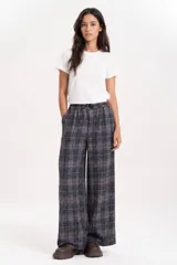 Pantalón wide leg de corte relajado con estampado de cuadros en tonos azul grisáceo y líneas terracota. Cuenta con cintura elastizada con cordón de ajuste y bolsillos laterales.
