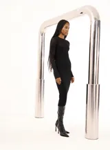 Vestido midi negro de tejido de punto acanalado, con cuello redondo y mangas largas. Presenta un panel de tejido calado en la parte superior del pecho.