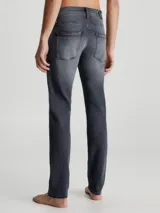 Pantalón de jean gris oscuro de corte slim, con cintura media, cinco bolsillos y cierre con cremallera.