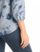 Buzo de tejido soft con estampado floral en tonos azules, cuello redondo y mangas largas con puños fruncidos.