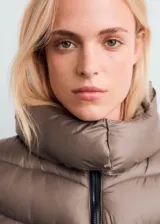 Chaqueta acolchada tipo puffer midi, color marrón topo, con diseño entallado, capucha, cuello alto y cierre de cremallera doble.