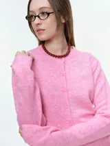 Cárdigan de punto color rosa, con cierre frontal de botones al tono, cuello redondo y mangas largas con puños acanalados.
