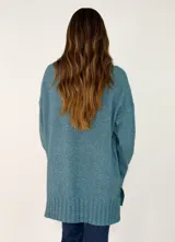 Sweater de punto color beige, de corte holgado y diseño oversize. Presenta cuello alto y puños con detalle de tejido trenzado, al igual que en el ruedo inferior.