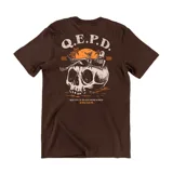 Remera de algodón color marrón con estampa gráfica en la espalda que presenta una calavera grande, un esqueleto relajado en una playa al atardecer y la inscripción Q.E.P.D.