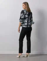 Blusa de gasa con estampado geométrico en tonos negro, gris y celeste. Tiene cuello redondo y mangas 3/4 amplias con abertura y botón.