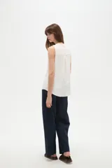 Musculosa de poliéster color blanco, con cuello en V y diseño holgado sin mangas.