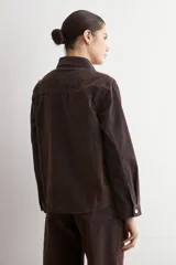 Sobrecamisa de jean con acabado simil terciopelo en color marrón oscuro, de corte recto, manga larga, cuello clásico y cierre frontal con botones metálicos.