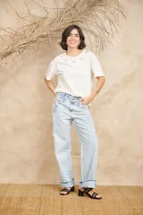 Jeans de corte ancho color celeste claro, tiro medio, con apliques bordados y desflecados en los laterales de la cintura y bolsillos, y dobladillo vuelto en los bajos.