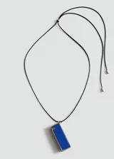 Collar largo con cordón negro ajustable y un dije colgante rectangular con detalles metálicos dorados y resina en tono azul.