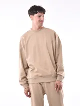 Buzo color arena de corte holgado, con cuello redondo y puños y cintura acanalados.