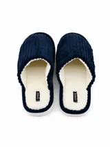 Pantufla abierta de pana azul marino con interior de corderito sintético color crema y suela plana.