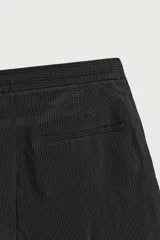 Bermuda relaxed fit de color negro, confeccionada en tejido fluido con viscosa y modal. Presenta cintura elástica ajustable con cordón, pliegues en el delantero, bolsillos frontales y bolsillos traseros de vivo.