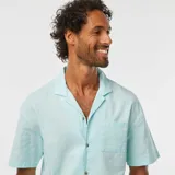 Camisa celeste de lino con cuello cubano, manga corta, cierre con botones y bolsillo en el pecho.