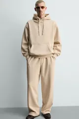 Pantalón jogger de corte relajado y pernera ancha, confeccionado en tejido de algodón con interior perchado. Presenta cintura elástica con cordón interior, bolsillos laterales y un bolsillo trasero de plastrón.