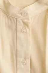 Blusa oversize en mezcla de algodón y viscosa, color amarillo claro, con cuello mao, botonadura frontal y mangas cortas abullonadas con terminación en broderie.