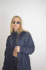 Campera de jean azul con cierre dorado, cuello clásico, mangas largas con puños elásticos y costuras blancas a contraste.