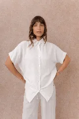 Camisa blanca de calce amplio y relajado, confeccionada en tejido liviano con textura sutil. Diseño oversize, con hombros caídos, mangas cortas amplias, cuello camisero y abotonadura frontal.