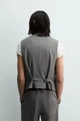 Chaleco de traje regular fit confeccionado en tejido con lana, con cuello en pico, cierre frontal de botones y bolsillos de vivo en la cintura. Presenta forro interior con diseño de rayas.