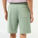 Bermuda verde de felpa ligera, de corte recto y holgado, con cintura elástica ajustable mediante cordón.