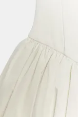 Mono corto confeccionado en hilatura de algodón de color blanco, con escote recto, tirantes finos ajustables y bajo con volumen abullonado.