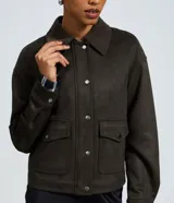 Campera bomber de gamuza sintética color verde oliva, con cuello estructurado, cierre frontal con botones metálicos y bolsillos delanteros con solapa.