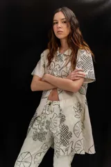 Vestido corto beige con estampado botánico en negro, cuello camisero, mangas cortas y cierre frontal con botones.