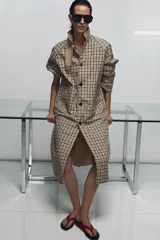 Trench reversible de Zara Woman Collection con diseño de cuadros en tonos beige, negro y tostado. Cuenta con cuello de solapa, cierre frontal con botones oscuros y bolsillos delanteros diagonales.