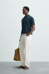 Polo de manga corta color verde azulado oscuro, confeccionado en tejido de punto con textura. Presenta cuello solapa y cierre frontal de botonadura.