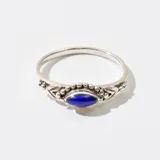 Anillo plateado con dije de piedra azul en forma de ojo.