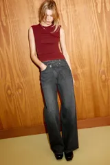 Jeans de tiro alto, color gris oscuro lavado, con pierna ancha extra larga (full length) y diseño de cintura cruzada asimétrica con cierre frontal de cremallera y botones metálicos.