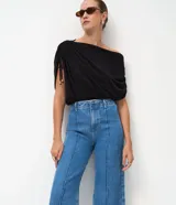 Pantalón de jean modelo wide leg cropped con cintura alta y sastre. Presenta costuras verticales frontales, bolsillos laterales y cierre delantero tradicional.