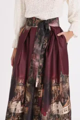 Falda midi de corte acampanado con estampado artístico de paisaje urbano. Presenta cintura alta con lazo ajustable del mismo tejido y diseño estructurado con pliegues.
